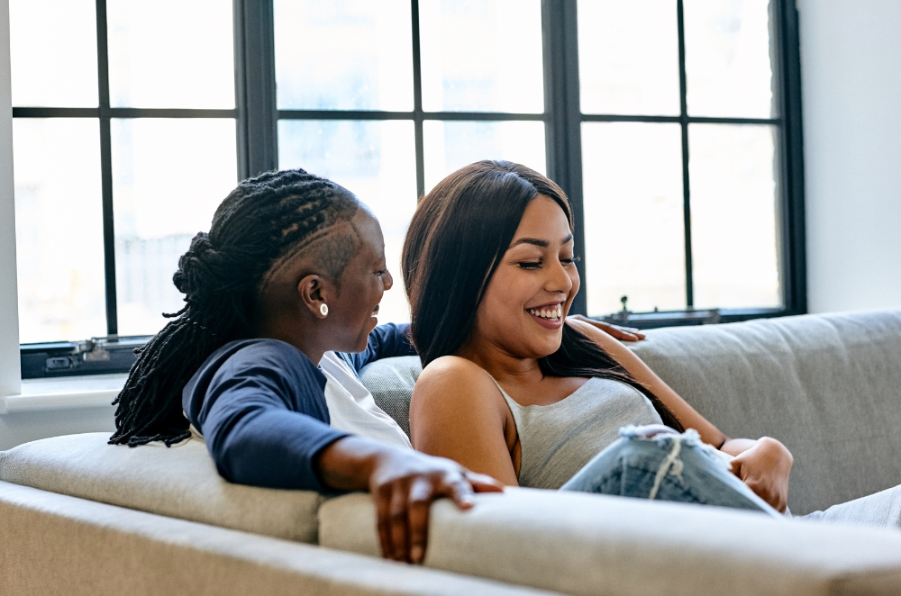 Couple sitting on the couch laughing.
