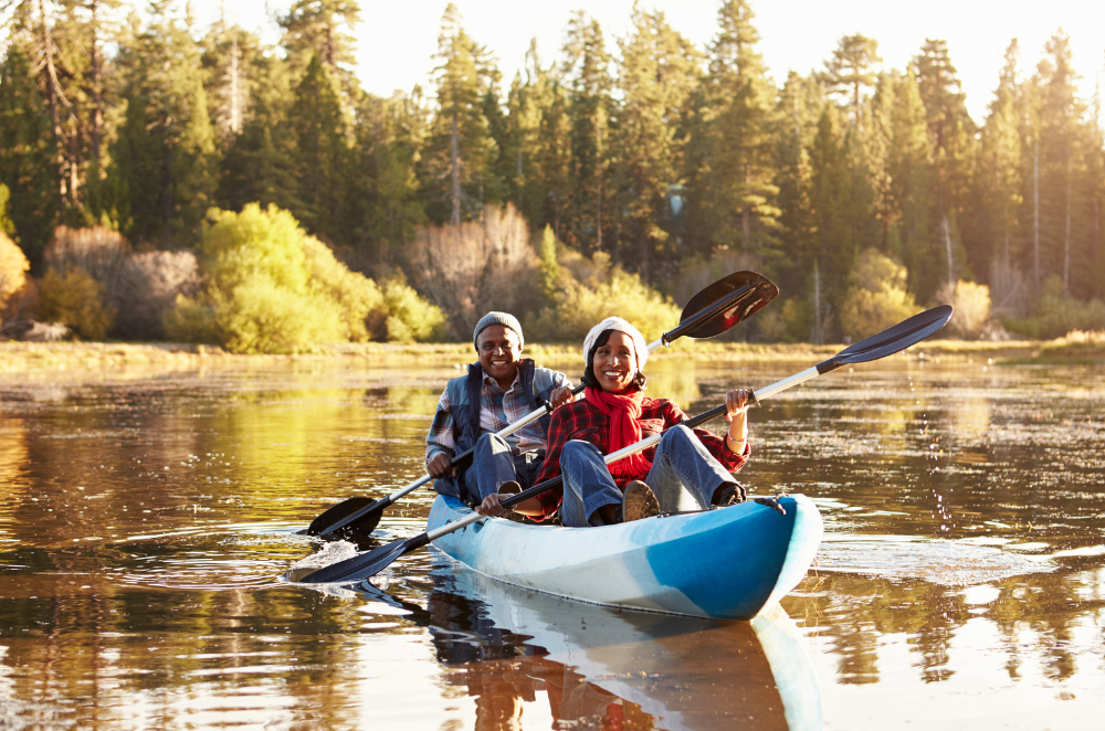 A middle aged couple canoeing in a river during fall season.